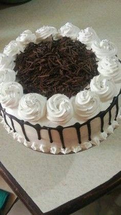 a cake with white frosting and chocolate shavings on the top is sitting on a table