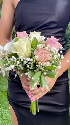 a woman in a dress holding a bouquet of flowers and greenery on the grass