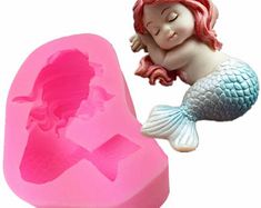 a pink heart shaped mold with a little mermaid laying on it's side next to the moulder