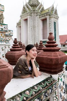 a woman sitting on top of a white and green wall next to a tall building