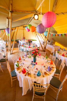 a large tent with tables and chairs covered in paper lanterns