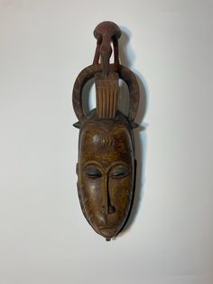 a wooden mask hanging on the wall with an iron ring around it's neck