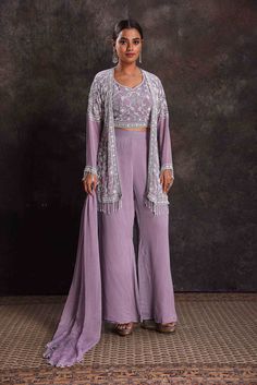 Get set to dazzle at sangeet night and festive occasions in this alluring lavender embroidered crop top and palazzo with shrug. Lavender Sharara For Eid Parties, Lavender Georgette Sets With Zari Work, Purple Floor-length Chikankari Embroidered Sharara, Lavender Festive Designer Wear Sets, Purple Chikankari Embroidered Floor-length Sharara, Luxury Lavender Georgette Sets, Lavender Sets For Eid Reception, Purple Floor-length Chikankari Embroidery Sharara, Lavender Georgette Sets With Resham Embroidery