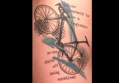 a tattoo with an image of a bicycle on it's side and words written in blue ink