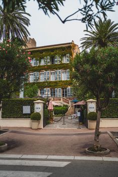 the entrance to an apartment building with trees and bushes around it on a city street