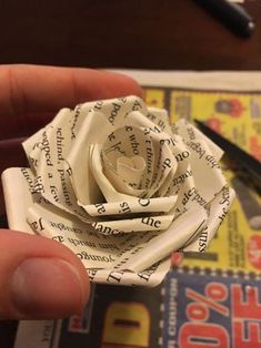 a person is holding a paper rose made out of newspaper