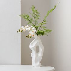 a white vase filled with flowers on top of a table