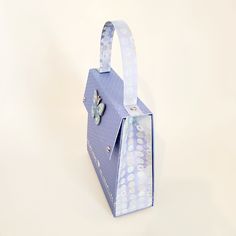 a paper bag with a butterfly on the side and polka dots around the handle, sitting on a white surface