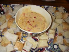 a bowl of soup is sitting on a plate with toasted bread and other food