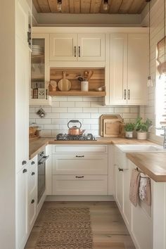 a kitchen with white cabinets and wood flooring is pictured in this image, there are wooden shelves above the sink