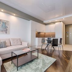 a living room filled with furniture next to a kitchen and dining room table on top of a hard wood floor