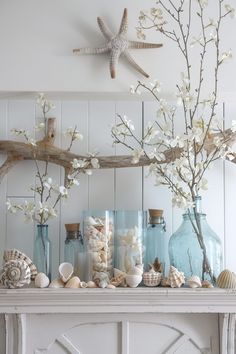 there are vases with flowers and seashells on the mantle