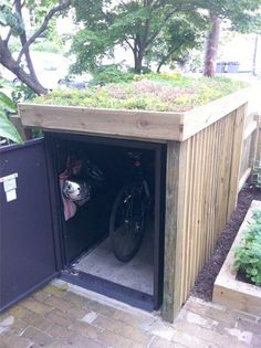 a bike is parked in the back of a wooden shed with plants growing on top