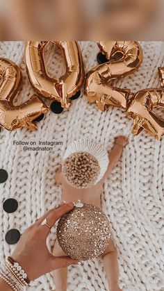 a baby laying on top of a white blanket next to gold foil balloons that spell out the word love