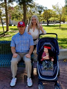 a man sitting on a bench next to a woman with a baby in a stroller