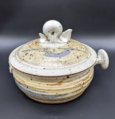 a ceramic container with an animal on it's lid sitting on a black surface