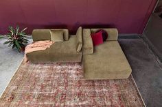 a large sectional couch sitting on top of a rug in front of a purple wall