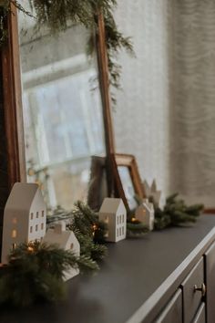 a mantle with christmas decorations on it and a mirror in the background