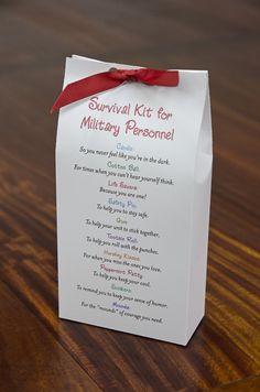 a small white box with a red ribbon on it sitting on top of a wooden table