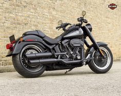 a black motorcycle parked in front of a brick wall