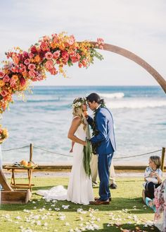 a bride and groom standing under an arch with flowers on it at their wedding ceremony