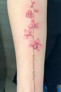 a pink flower tattoo on the left side of the arm with words written in cursive writing