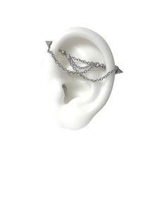 a pair of ear piercings on top of a white headpiece with chain attached to it