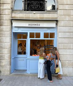 two women are standing in front of a store