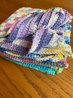 a stack of crocheted blankets sitting on top of a wooden table