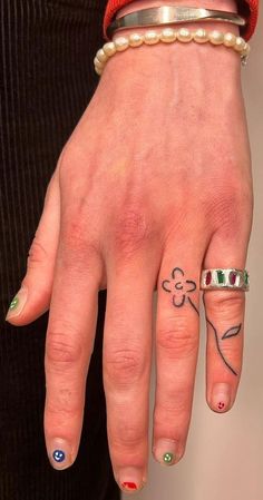 a woman's hand with tattoos and rings on it