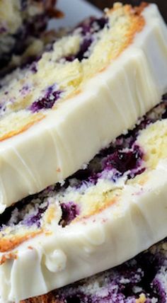 three slices of cake with white frosting and blueberry toppings are stacked on top of each other