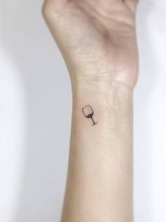 a woman's wrist with a small wine glass tattoo on the left side of her arm