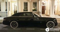 a black car parked on the street in front of a building with white pillars and windows