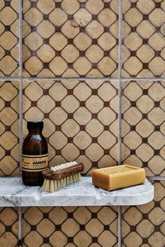 a bottle of soap sitting on top of a counter next to a brush and sponge