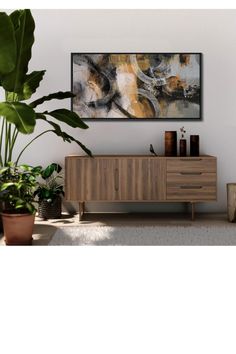 an abstract painting hangs on the wall above a wooden cabinet with two plants in it