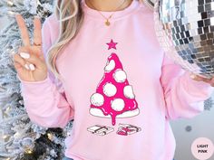 This unique and fun Pizza Christmas Tree Sweatshirt is made of soft cotton and polyester. It is the perfect Holiday sweater for celebrating the festive season in style. The collar is ribbed knit, so it retains its shape even after washing. Side seams are constructed to ensure they are smooth and there is no itching.  The pink Christmas shirt features a hot pink and white pizza Christmas tree print on the front of the crewneck. Underneath the tree are two pizza boxes. It is available in sizes S to 5XL (see size chart) and in Heliconia Pink and Light Pink. This Holiday sweatshirt is a perfect pink Christmas shirt gift for her and him. If you like this Holiday shirt, then check out our store for our full Christmas range that includes apparel, home decor and gifts. We also have this pizza Chri Pink Long Sleeve Festive Tops, Pink Long Sleeve Tops For Festive Occasions, Holiday Pink Long Sleeve Tops, Pink Long Sleeve Holiday Top, Pink Cotton Holiday Sweatshirt, Pink Festive Winter Top, Pink Graphic Print T-shirt For Winter, Winter Pink Graphic Print T-shirt, Pink Tops As Winter Gifts