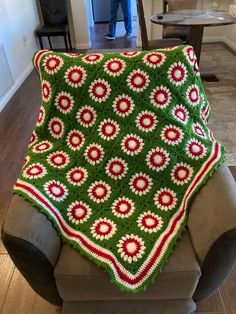 a green and red crocheted blanket sitting on top of a couch in a living room