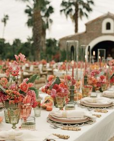 the table is set with pink flowers and place settings for an outdoor dinner party or celebration