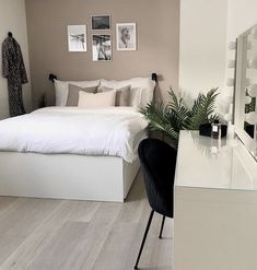 a white bed sitting next to a mirror on top of a wooden floor in a bedroom