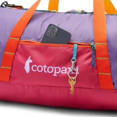 a pink and purple duffel bag with a cell phone in it's pocket