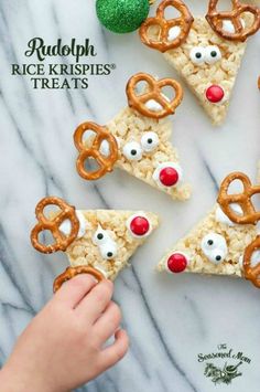 a hand is picking up some pretzel treats from the tray with reindeer faces on them