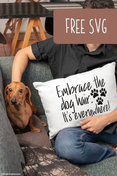 a man sitting on a couch holding a pillow that says embrace the dog hair it's everywhere