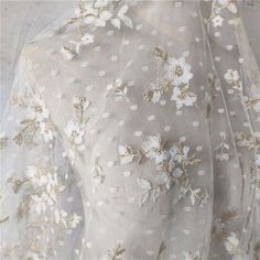 the back of a white dress with gold and white flowers on it's sleeves