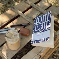 an open book sitting on top of a wooden table next to a jar of liquid