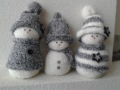 three snowmen are standing next to each other on a shelf in front of a white wall