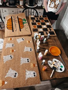 a person standing in front of a wooden table with paint and brushes on top of it