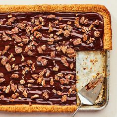 a chocolate dessert with pecans on top and a spoon in the middle, ready to be eaten