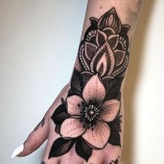 a woman's hand with a flower tattoo on it