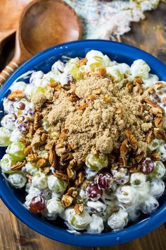 a blue bowl filled with grapes, nuts and crumbled breadcrumbs