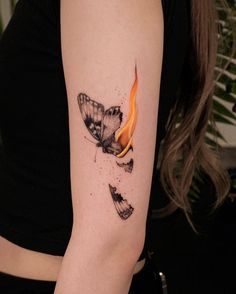 a woman's arm with a butterfly and fire tattoo on the left side of her arm